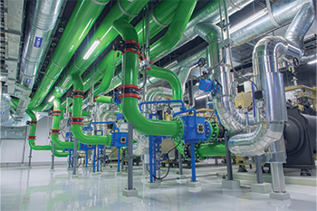 Industrial chiller plant with green piping, pumps, valves, and HVAC mechanical equipment